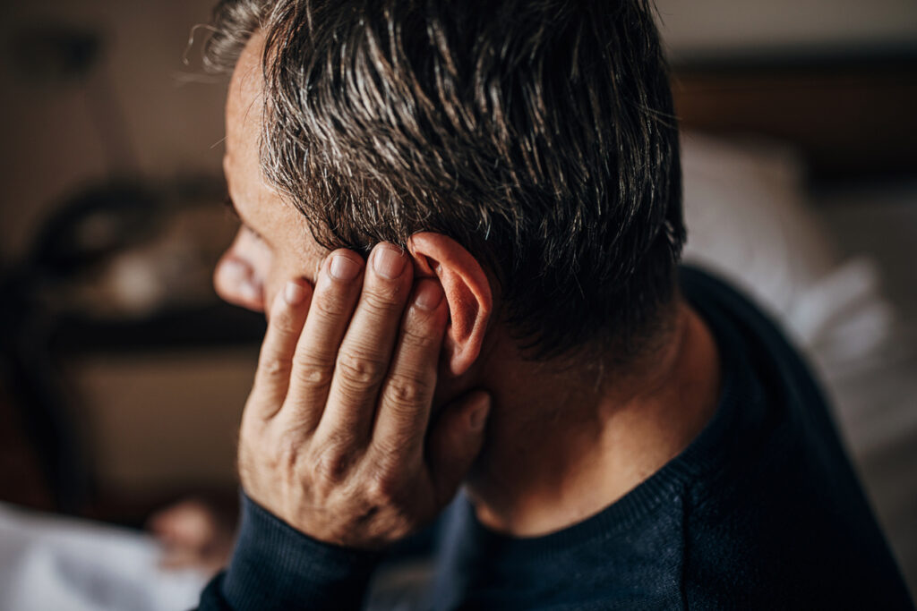 A close-up of a man holding his hand to his ear