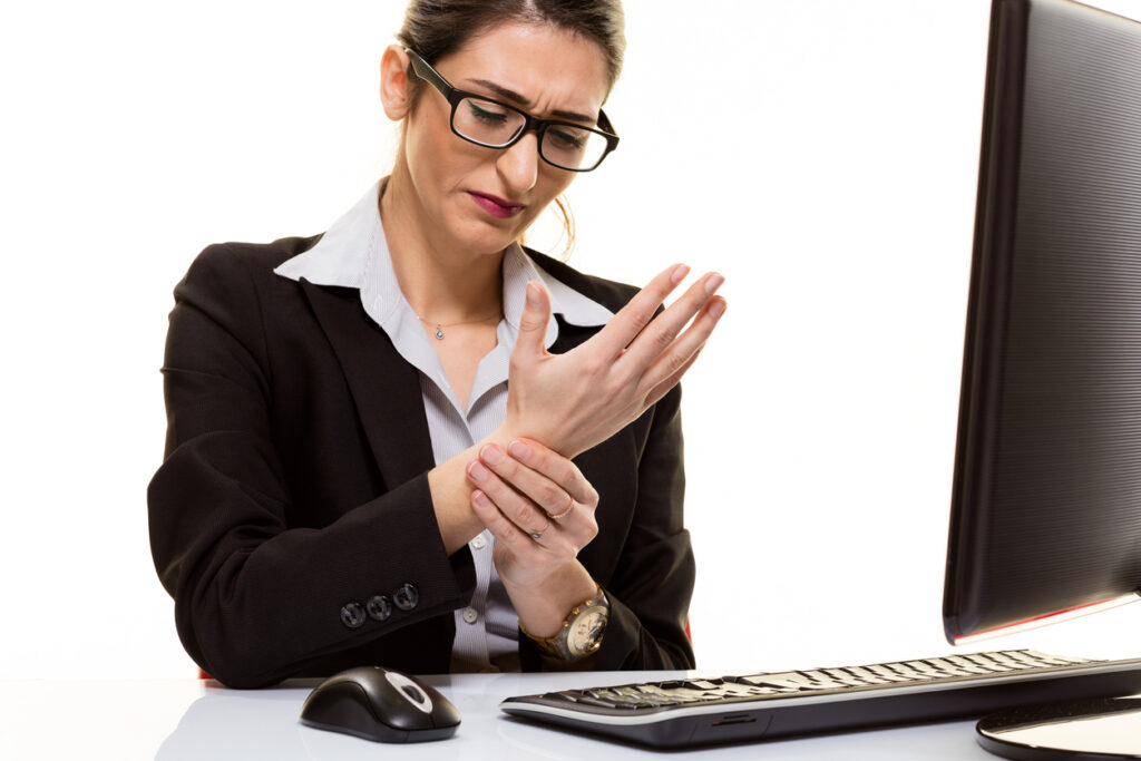 Person at computer holding wrist in pain