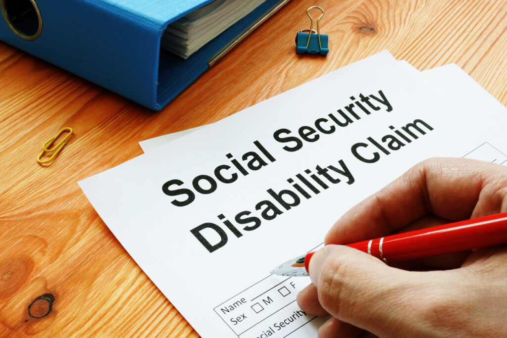 Close-up of a man filling out a Social Security Disability claim with a red pen.