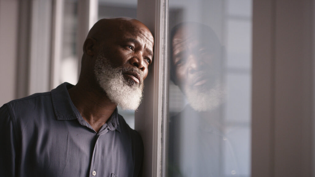 Depressed man leaning against a window