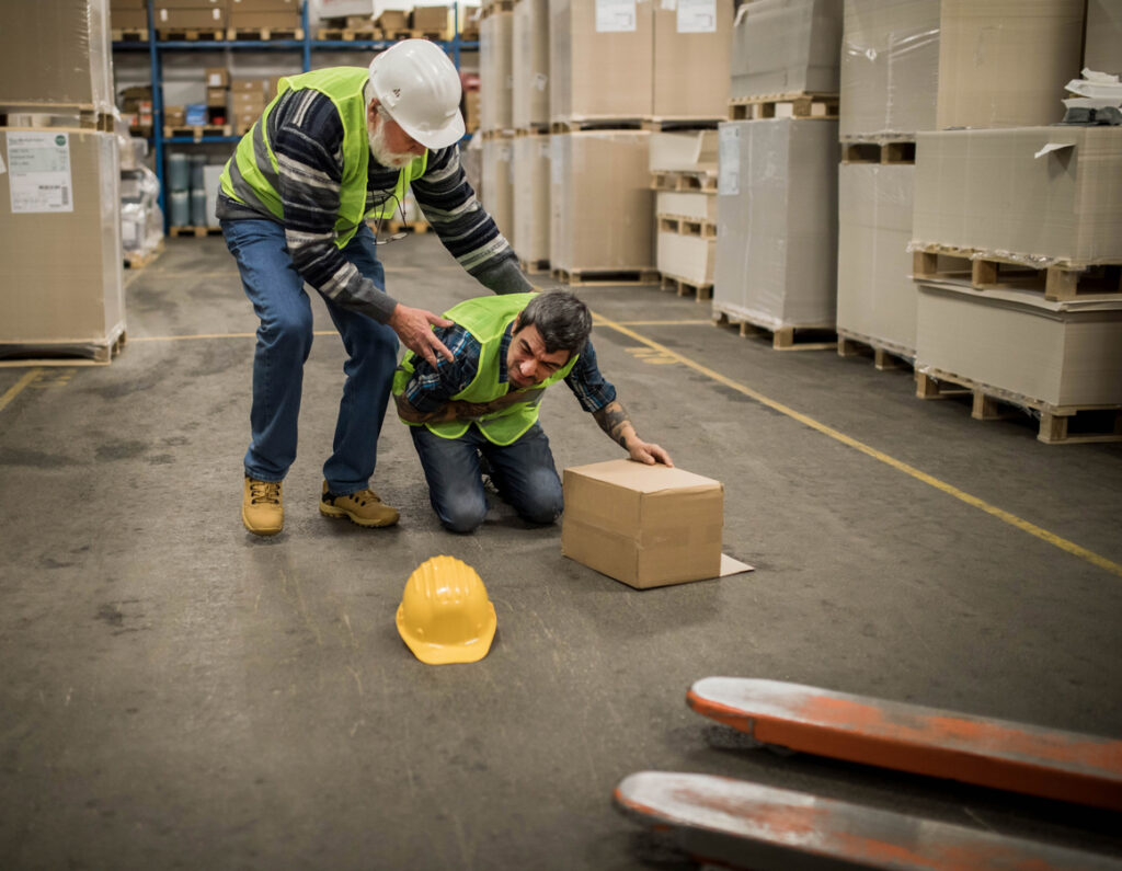 Older man in white hardhat helping injured coworker