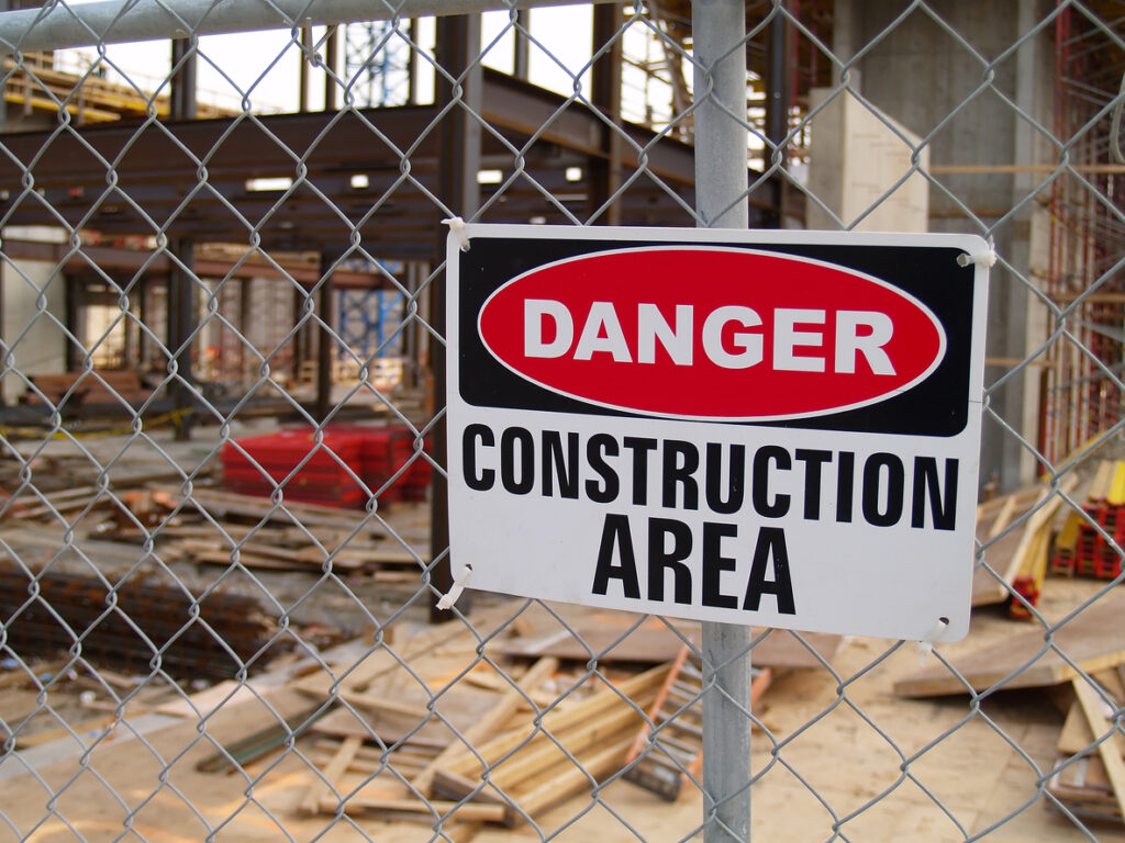 A sign that says “Danger: Construction Area” on a chain link fence