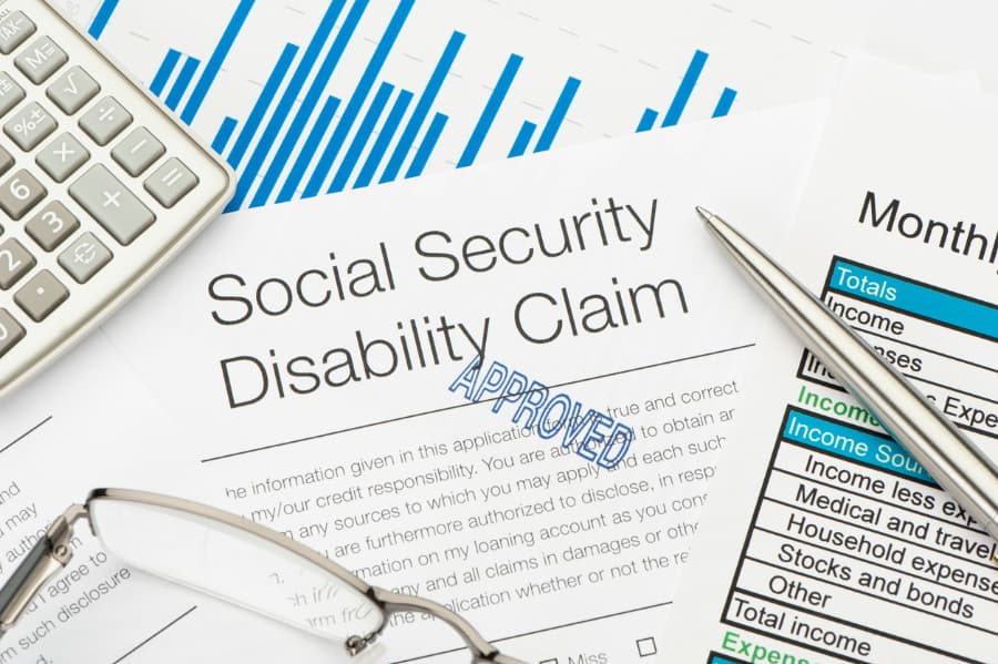 Close-up of an approved Social Security Disability claim with a calculator, pen, and eyeglasses