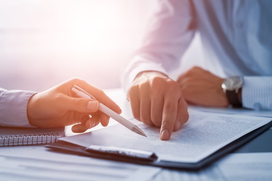 Close-up of two men’s hands going over a form on a clipboard with pen in hand